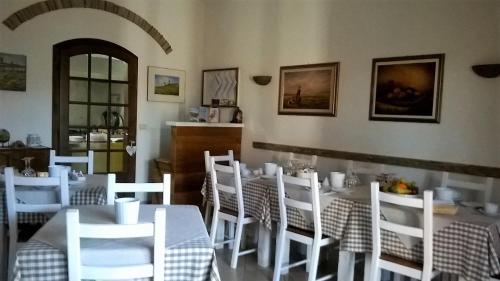 un comedor con mesas blancas y sillas blancas en Agriturismo Vallerana en Capalbio