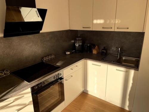 a kitchen with white cabinets and a stove and a sink at Ferienwohnung in Unterwössen in Unterwössen