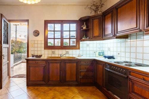 a kitchen with wooden cabinets and a window at Artemida Beachside Villa Escape - 50m by the Sea in Artemida