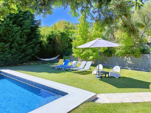 a swimming pool with chairs and an umbrella next to a swimming pool at Casa da Gardunha in Cortiçada