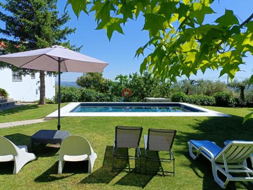 a group of chairs and an umbrella next to a swimming pool at Casa da Gardunha in Cortiçada