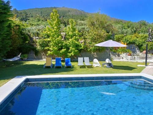 a swimming pool with chairs and an umbrella at Casa da Gardunha in Cortiçada