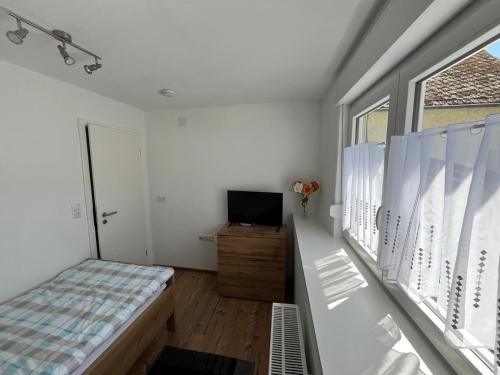 a bedroom with a bed and a tv and a window at Ferienwohnungen und Appartements - Haus Budinger in Alf