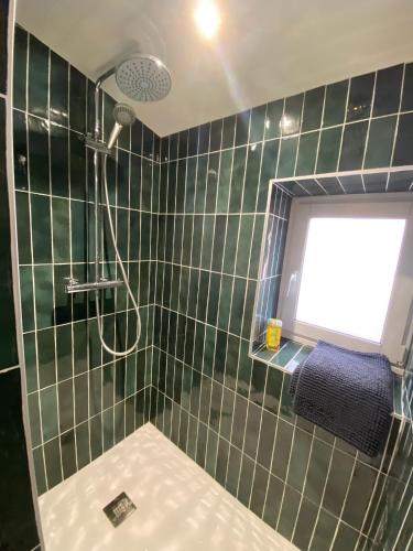 La salle de bains carrelée de couleur verte est pourvue d'une douche et d'une fenêtre. dans l'établissement Les Nids de Galleben La Villa Landaise, à Liposthey