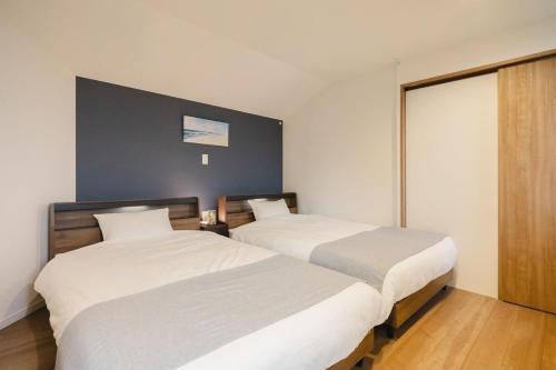 two beds in a room with white walls and wood floors at Private Villa AZUL 南房総 千倉 海徒歩4分 ペット可 サイクリスト対応 in Minamiboso