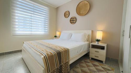 a white bedroom with a bed and a window at Descanso & Confort Girardot in Girardot
