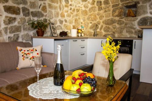 a table with a bowl of fruit and a bottle of wine at Apartmani Stone oasis in Zupci