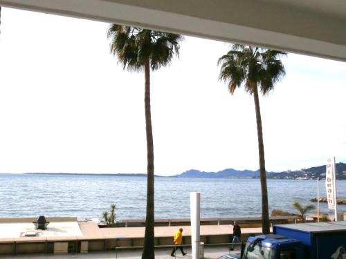 a view of the water and palm trees from a building at Iberia Beach Front Sea in Juan-les-Pins