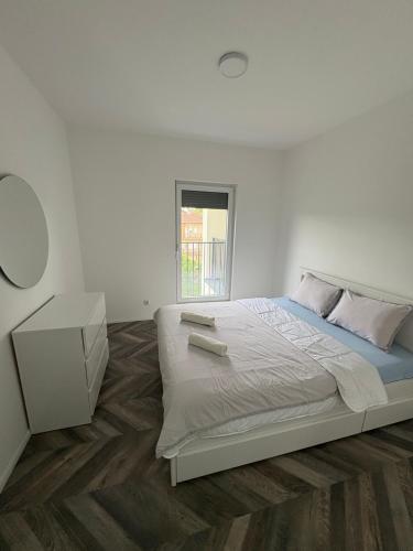 a white bedroom with a large bed and a table at Tians Apartment in Prishtinë