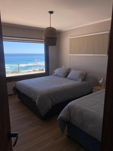 a bedroom with two beds and a view of the ocean at Frente al Mar - Punta de Choros Casa La Changa in La Higuera