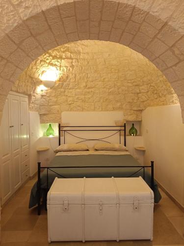 a bedroom with a bed and a stone wall at Trullo Le Tre Sorelle in Cisternino