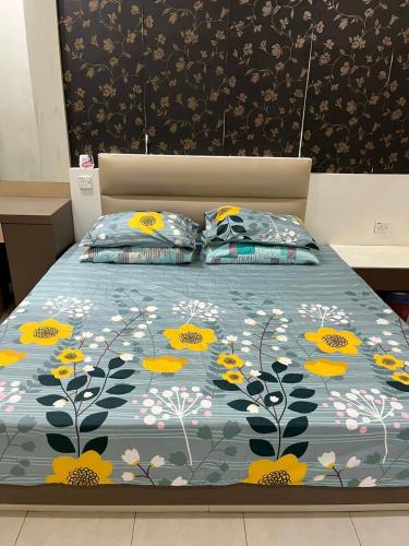 a bed with a blue comforter with yellow flowers at Rumah Armand Masjid Tanah Ria 3 , 4BR Fully Aircond Masjid Tanah Melaka in Masjid Tanah