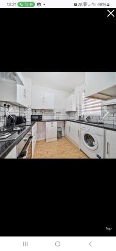a large kitchen with white cabinets and a washer at The Wheatland House in London