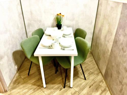 a white table with green chairs and flowers on it at Oasis Valley in Karlovy Vary