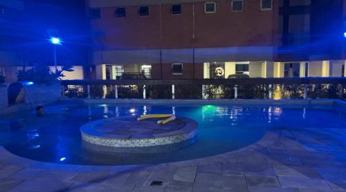 a swimming pool at night with a hotel at Cobertura Aconchegante na Enseada 3 Quartos, Piscina e Conforto a Poucos Passos do Mar in Guarujá