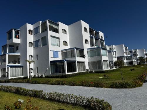 a large white apartment building with a lawn in front of it at Mirador Capo Negro in Cabo Negro