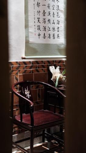a chair in a room with writing on the wall at Wuhe Hotel in Hsia-shih