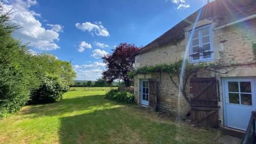 an old stone house with a green yard at La Bergerie in Thollet