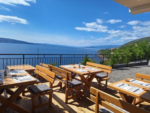 una fila di tavoli e sedie in legno su un balcone di SUZANA Beautiful balcony sea view 1 a Senj