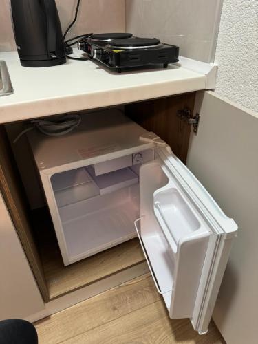 an open refrigerator under a desk with a microwave at Apartments HAN 2 Sarajevo in Sarajevo