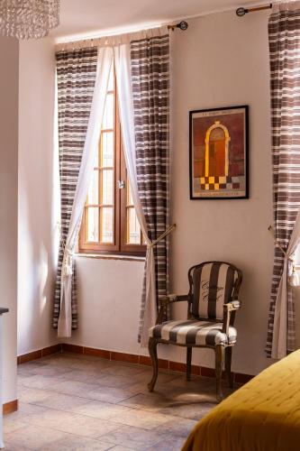 a bedroom with a chair and a window at La Vieille Demeure in Torreilles
