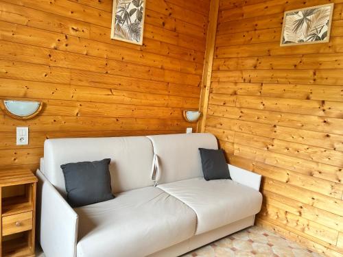 a white couch in a room with wooden walls at Résidence Les Dômes in Murol