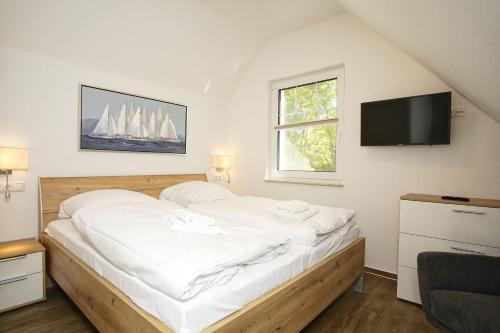 Un dormitorio con una cama con un televisor de pantalla plana. en Rex Rugia FeWo17-7 mit Schwimmbad und Saunanutzung im AHOI-Erlebnisbad Sellin, en Lobbe