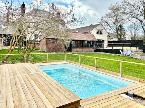une piscine avec une terrasse en bois et une maison dans l'établissement Le clos de Montherlant, à Saint-Crépin-Ibouvillers