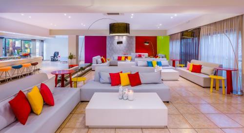 a living room with white couches and colorful pillows at Kipriotis Hippocrates Hotel in Kos Town