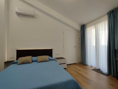 a bedroom with a blue bed and a large window at DH Studio Apartments in Castellammare del Golfo