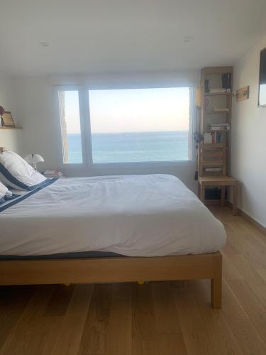 un lit dans une chambre avec une grande fenêtre dans l'établissement TY KERVIGORN les pieds dans l'eau, à Saint-Pabu