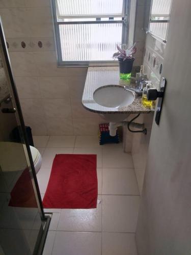 a bathroom with a sink and a red rug at Vanderli - Deli in São Vicente