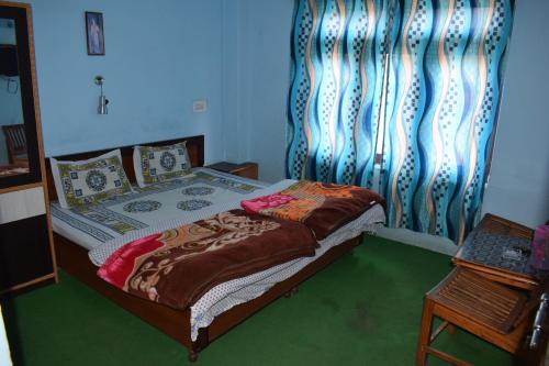 a bedroom with a bed with a curtain and a table at Khandroling Guest House in Kyelang