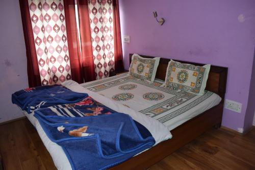 a bedroom with a bed with blue sheets and pillows at Khandroling Guest House in Kyelang