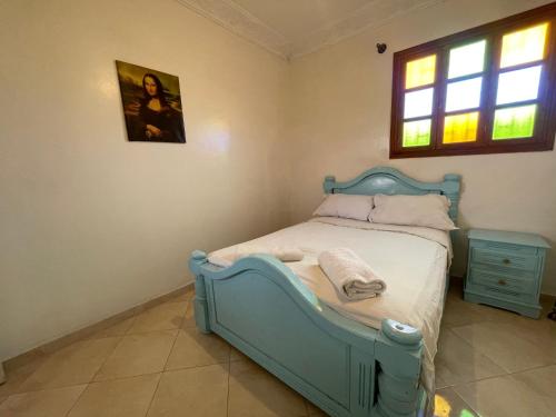 a bedroom with a blue bed and a window at Hotel Maison Olga in Meknès