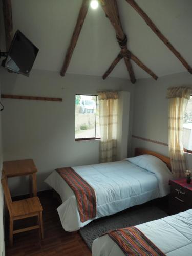 a bedroom with two beds and a flat screen tv at Lodge Wayra Wasi in Coporaque