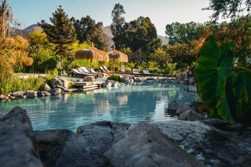 a pool of water with rocks and umbrellas at Hotel Boutique Refugio El Molle in El Molle