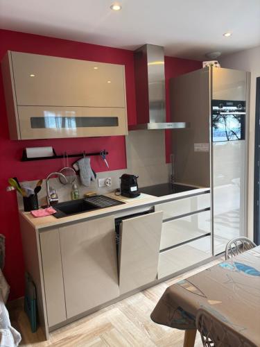 - une cuisine avec des placards blancs et des murs rouges dans l'établissement Appartement T2 Sanary sur mer, à Sanary-sur-Mer