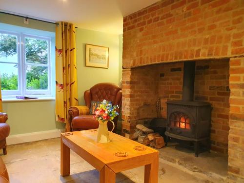 ein Wohnzimmer mit gemauertem Kamin und Tisch in der Unterkunft East View Cottage iow in Chalegreen
