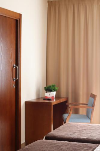 a room with two beds and a desk and a chair at HOTEL ARZÚA in Arzúa