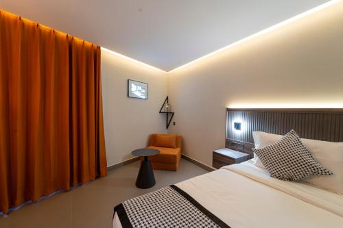 a bedroom with a bed with an orange curtain and a chair at Hill Top Hotel in Aqaba