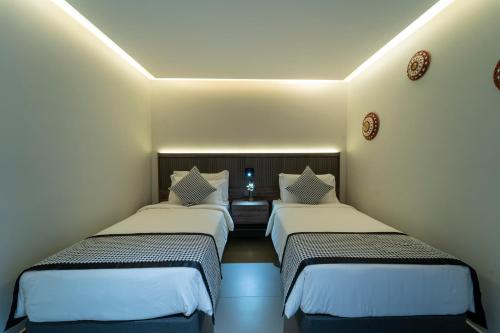 two beds in a small room with white walls at Hill Top Hotel in Aqaba