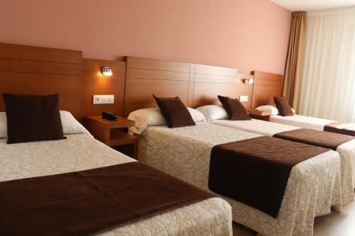 a hotel room with three beds and a window at HOTEL ARZÚA in Arzúa
