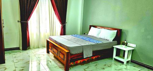 a bed in a green room with a window at Ananyah Villa in Trincomalee