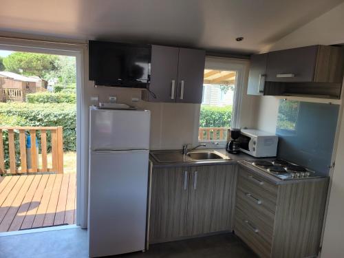 une cuisine avec un réfrigérateur blanc et un évier dans l'établissement mobile home climatisé, 3 chambres, à Port-la-Nouvelle