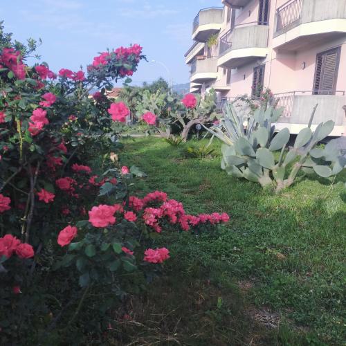 a garden with pink flowers in front of a building at aranceto dell'Etna in Mascali