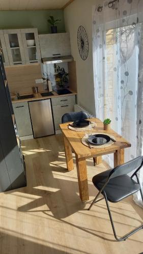 a living room with a wooden table and a kitchen at Le cabanon in Le Massegros