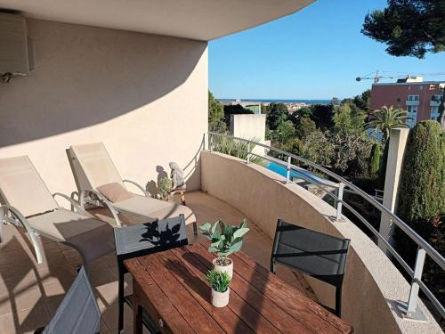 d'une terrasse avec une table et des chaises en bois sur un balcon. dans l'établissement T3 vue mer, 2 chambres, piscine, terrasse, parking public gratuit à 150m, à Cannes