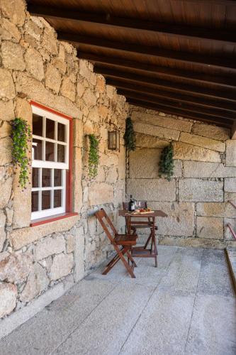 a wooden table in front of a stone building with a window at House Sopo in Vila Nova de Cerveira