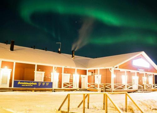 a building with the green northern lights in the sky at Ylläksen Eväskorin Huoneistot in Äkäslompolo